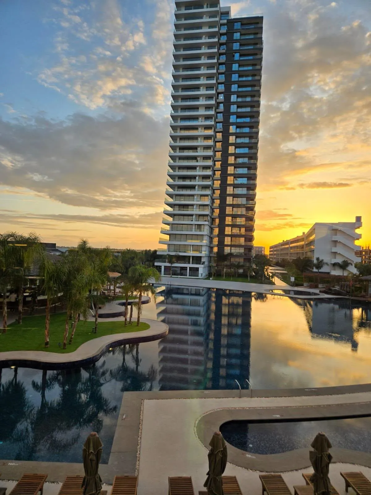 Infinity-Pool eines Resorts in Iskele bei Sonnenuntergang mit Hochhaus-Spiegelung im Wasser, Nordzypern