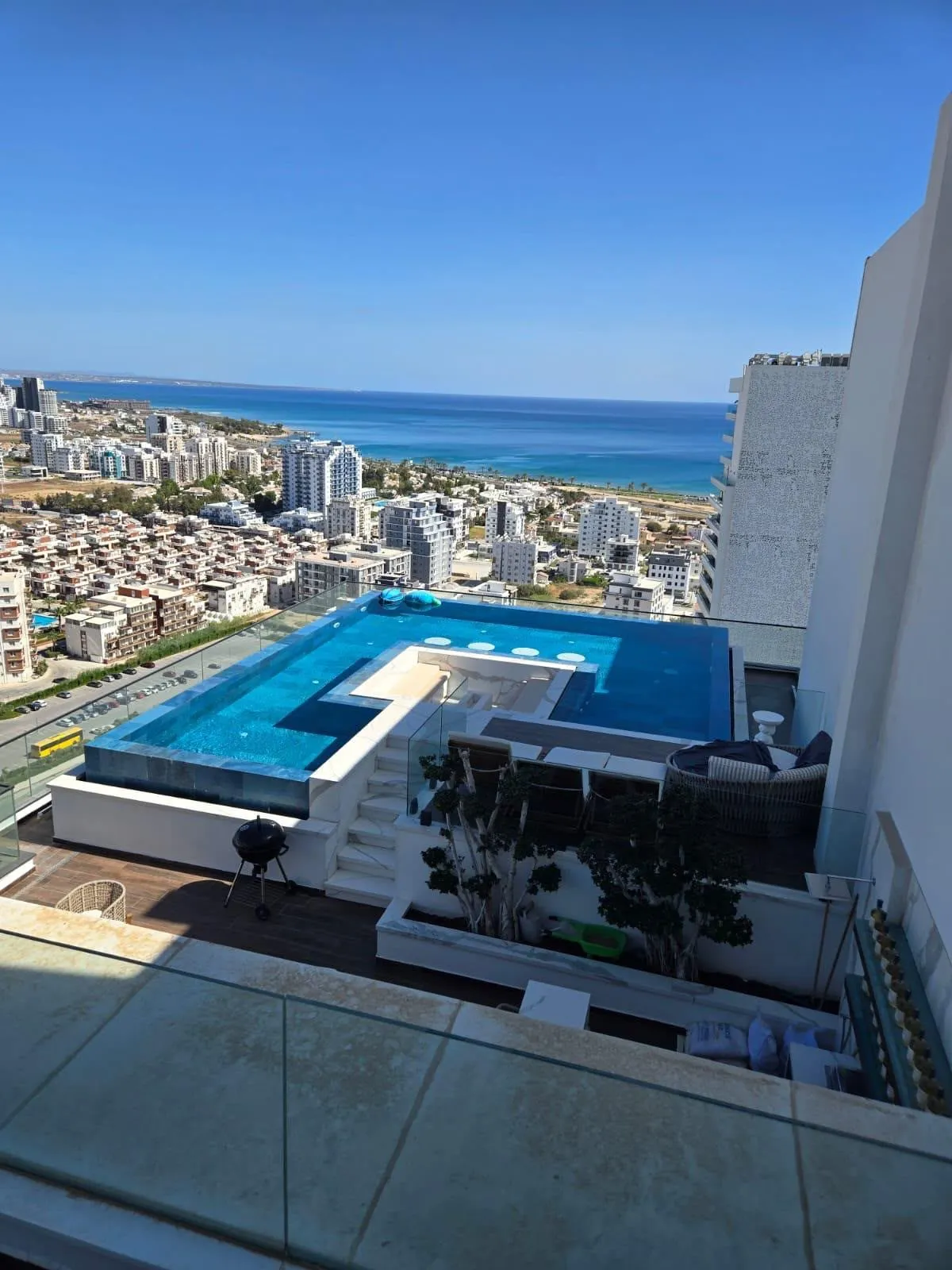 Dachterrassen-Infinity-Pool in Iskele bei Tag mit Blick über die Stadt aufs Meer, Nordzypern